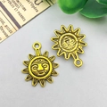 Close-up of two vintage gold sun face charms with radiating rays for DIY jewelry making - Antique Gold Sun