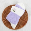 Chaussettes épaisses pelucheuses violettes et blanches sur plateau en osier et tapis doux - Violet