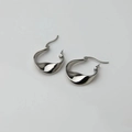 Macro shot of silver-colored irregular twisted wave hoop earrings with polished finish - Irregular Torsion Hoop / Silver