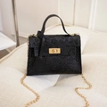 Detalle de bolso negro de moda con grabado de dibujos y cierre giratorio dorado - Negro