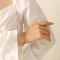 18k vergulde armband met roze zirkoon en getextureerde ringen om de pols van model - Roze Zirkoon Armband-17cm