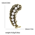 Detailed view of feather alloy brooch with white pearls and brushed metal texture - Antique Gold