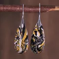 Macro shot of teardrop earrings with black and yellow marble swirls on a rustic branch - Black Yellow White Marble Texture Style (ER1025-12)