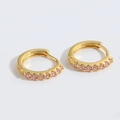 Detailed view of gold huggie earrings with a row of prong-set pink cubic zirconia stones - Pink