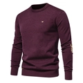 Detail eines weinroten Rundhalspullovers mit enger Strickstruktur und Metall-Brustlogo - S / Burgunderrot