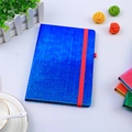 Détail d'un carnet pailleté bleu avec élastique rouge sur un bureau blanc stylé - A5 / Bleu