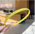 Slim yellow satin headband with jelly color finish held against a soft background - Yellow