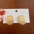 Matte gold irregular oval earrings on a white card display with wood background - Brushed Gold