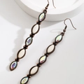 Macro view of vintage bronze bohemian dangle earrings with marquise stones and crystals - Long AB White