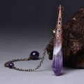 Macro detail of hexagonal amethyst pendulum with vintage bronze hollow metal cap on wood - Antique Bronze Amethyst