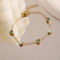 Détail du bracelet double couche cœur doré orné de cinq zircons bleus sur une surface réfléchie - Cœur bleu