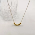 Minimalistische goldene Titanstahlkette mit fünf ovalen Perlenanhängern an einer feinen Kette - Reiskorn-Stil