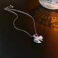 Details einer Kette mit rosa Herz-Zirkon und silbernem Schleifenanhänger auf dunklem Grund - Rosa Herz Schleife Halskette