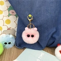 Detailed view of a pink fluffy plush keychain with cute sunglasses on a denim background - Pink
