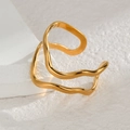 Detalle de anillo ondulado de doble capa bañado en oro de 18K sobre superficie blanca - Estilo Curva de Onda