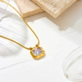 Vista de cerca de cadena de serpiente dorada con colgante de circón en fondo texturizado - Collar de Oro y Circonita Blanca