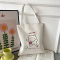White canvas tote bag with cute cartoon bear and Happy slogan print in lifestyle setting - White with HAPPY Bear