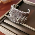 Detailopname van een vintage gevlochten open zilveren armband op een donker lederen tray - Zilver