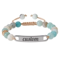 Macro detail of custom engraved metal plate on pink zebra stone beaded bracelet - Amazonite