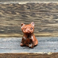 Detailed view of hand-carved red and black spotted gemstone French Bulldog on wood surface - Mahogany Obsidian