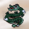 Detail of green enamel dragon pin with black outlines and red tongue on silk background - Auspicious Dragon 4 (Green)