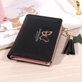 Short black bifold wallet with gold butterfly charm and tassel on a wooden background - Black