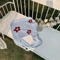 Detail der hellblauen Stricktasche mit roten Blumen auf einer weißen Gartenbank - Hellblau