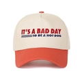 Detailed embroidery view of 'IT'S A BAD DAY TO BE A HOTDOG' text on color-block cap - Orange Red