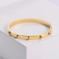 Elegante brazalete de acero de titanio dorado con remaches cónicos en base blanca - Dorado