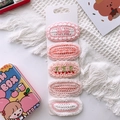 Gros plan de cinq barrettes en tricot fait main avec motifs fleurs et cerises sur carte - Style Nœud/Cerise / Ensemble Rose