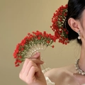 Elegante gouden waaiervormige haarkam met rode bloemen gedragen door een model in actie - Rood