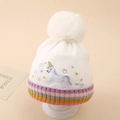 Detailed close-up of a white knit unicorn hat with a large fur pompom and colorful stripes - One Size (2-5 Years) / White