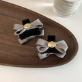Detail of gray fabric bow hair clips with gold circular charms on a wooden tray - Gray