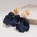 Dettaglio di orecchini a fiore in acrilico blu opaco con foglia dorata su una pietra - Blu scuro