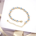Macro detail of Bohemian evil eye bracelet with blue enamel, cubic zirconia and gold plating - White