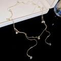 Detail einer vergoldeten Halskette mit Zirkonia-Anhängern und zarten goldenen Perlen - Gold