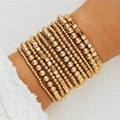 Detail of layered gold beaded bracelets with round and square beads on a model's wrist - Gold 11-Piece Set