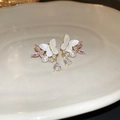 Detalle de pendientes de lazo con circón rosa y cristal sobre bandeja de cerámica - Pendientes de Botón de Mariposa Perla Gota de Agua con Aguja de Plata (Oro-Blanco-Rosa)