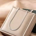 Sleek silver stainless steel flat snake bone chain necklace on champagne velvet box - Necklace / Silver
