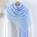 Solid blue crinkled cotton linen scarf for women hanging on a wooden hanger with fringe edge - Blue