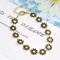 Elegant gold necklace with black and yellow daisy flower pendants on water ripple background - Large Flower Bracelet / Black