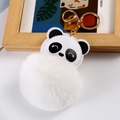 Nahaufnahme von Panda-Schlüsselanhänger mit weichem Plüschball und goldenen Metall-Details - Weiß