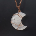 Macro detail of moon-shaped crystal pendant with handcrafted copper wire wrap and chain - White Crystal