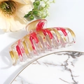 Macro detail of large marble red hair claw clip with golden glitter on marble tray - Red