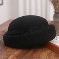 Detailansicht der schwarzen Wollfilz-Baskenmütze mit Netzschleier auf Holztischplatte - M(56-58cm) / Schwarz