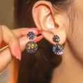 Sparkling dark blue and bright yellow rhinestone snowflake clip-on earrings on model - Starry Black
