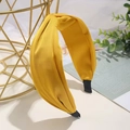 Elegante diadema de satén amarillo con diseño de nudo cruzado sobre un fondo minimalista - Amarillo