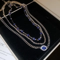 Close-up of silver layered evil eye necklace with blue rhinestones in a black velvet box - Three-Piece Set / Silver
