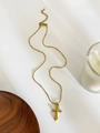 Dettaglio di un ciondolo a croce placcato oro con catena a perline su sfondo bianco - Croce classica testurizzata