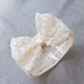 Elegant beige lace baby headband with large bow detail on soft textured background - Beige Lace Bow